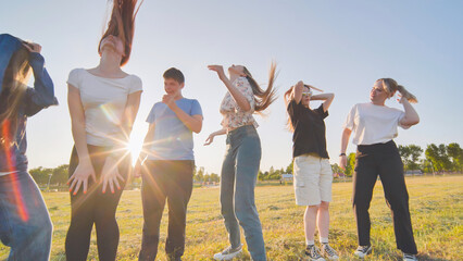Obraz premium Funny jolly friends dancing in the city meadow in the evening.