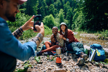 Young happy women being photographed by their friends during their hiking weekend in mountains.