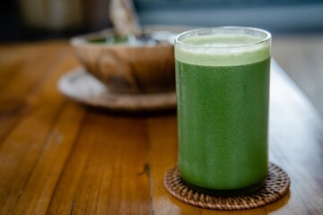 Glass of green celery juice on wooden table