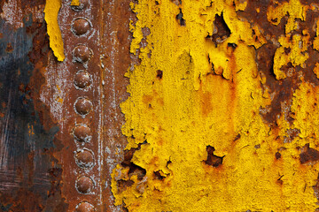 beautifully rusted rivetted sheet metal with leftovers of yellow paint texture and full-frame...