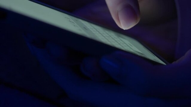 Text message with mobile phone. Side view of a smartphone in a woman's hand macro shot. Woman texting sms with smartphone. Catfish or digital scam. Screen keyboard in instant messaging chat.