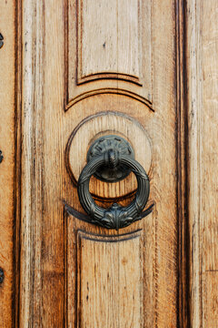 Brown wooden door with brass knocker. Old elegant metal door handle