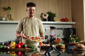 Medium shot of young middle eastern influencer demonstrating food to smartphone camera while making...