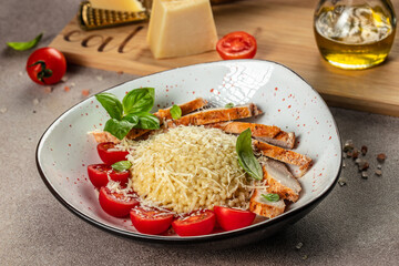 chicken breast with ptitim pasta, cherry tomatoes and cheese on a light background. top view. copy space for text