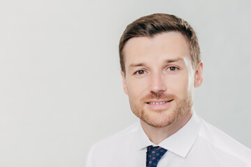 Polished businessman with a warm smile, poised in a white shirt and patterned tie, portrait style