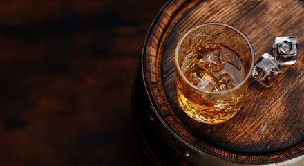 Whiskey glass with ice on a rustic barrel, a classic sip