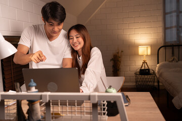 Happy Asia couple working with computer notebook in night time at home	