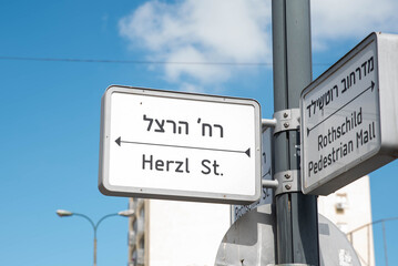 Urban city navigation street name sign, crossroad corner Rothschild and Herzl in Rishon Lezion, Israel