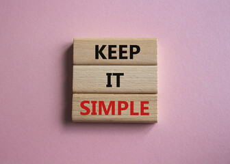 Keep it Simple symbol. Concept words Keep it Simple on wooden blocks. Beautiful pink background....