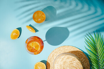 Summer refreshing cocktail aperol spritz with orange and palm leaves on a blue background with...