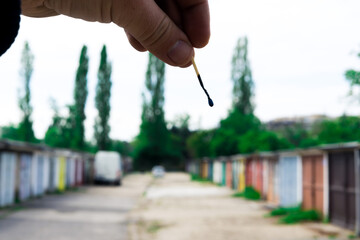 A match, a hand with a matches against the background of old garages in city.