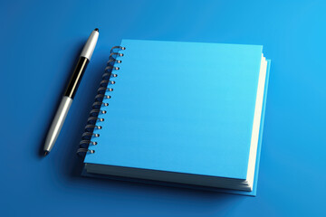 A blue notebook with a pen placed on top. Perfect for office supplies and stationery concepts.