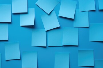 A collection of blue post-it notes attached to a blue wall. This versatile image can be used for various purposes, such as office organization, brainstorming, or reminders.