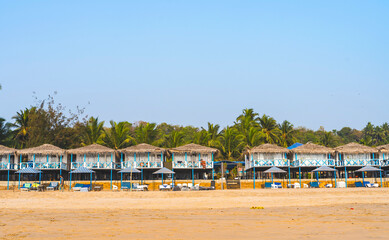 Colorful huts in Agonda beach with palm trees background in Goa, India