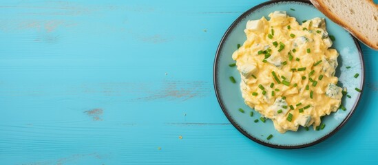Scrambled eggs with onion and chives on a blue plate Top view copy space image - obrazy, fototapety, plakaty