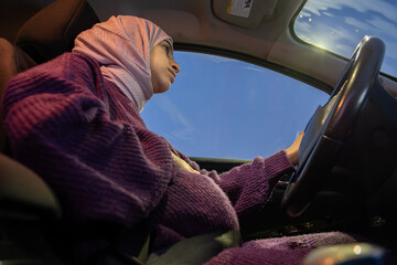 Pregnant arabic muslim woman driving car at night wearing winter clothes ,hijab and seat belt...