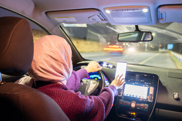 arabic muslim woman driving car at night wearing winter clothes ,hijab and seat belt driving in...