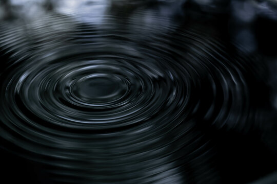 Ripple of water or water drop splash on black background. Abstract shape out of the water