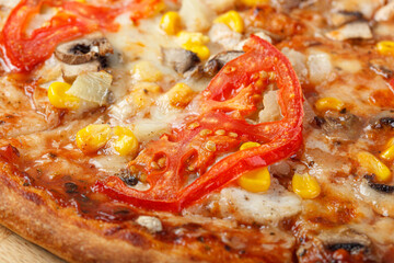 delicious pizza with chicken, mushrooms, cheese, tomatoes and corn on a wooden background