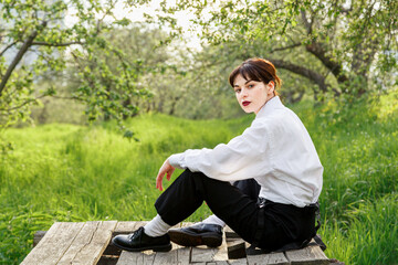 A beautiful girl in a white shirt, in black trousers with suspenders against the background of the...