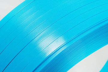 blue polyester tape on a white background. high-strength temoplastic tape in a roll on a light...