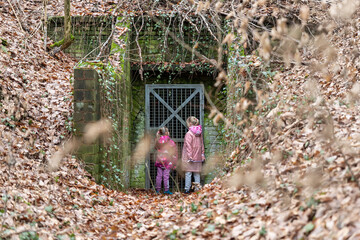 Two little girl friends kids stay at entrance of old abandoned entrance door of scary underground...