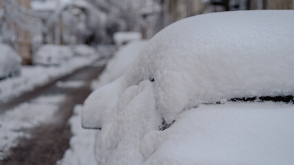 Cars covered with snow from the first snow fall of the year. Winter concept, snowy cars parked on...