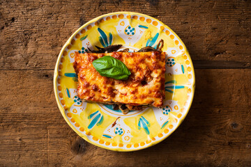 top view plate with eggplant parmigiana, wooden background