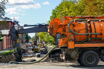 City street rebuilding view, combined vacuum suction and canal jetting machine in foreground - obrazy, fototapety, plakaty