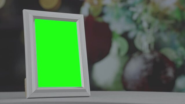 Green colored empty space inside of wooden photo frame standing in room against Christmas decor background close up