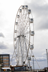 The Ferris wheel attraction is large against the backdrop of a cloudy, textured sky. Vertical photo