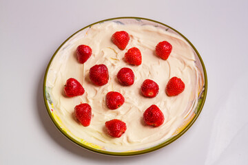 Fresh juicy strawberries in whipped cream in a plate on the table.