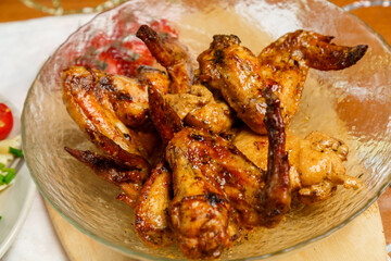 A large transparent plate with grilled chicken wings with a crispy crust