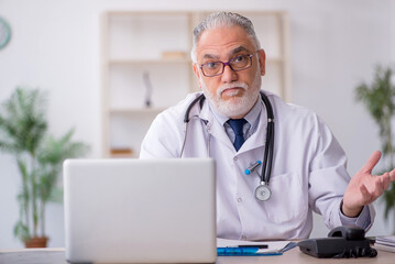 Old male doctor sitting in the clinic