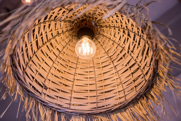 Decorating hanging lantern made from bamboo. rattan chandeliers different forms on wooden wall background. Straw lampshade in cozy living room. Eco-friendly interior design using natural materials.