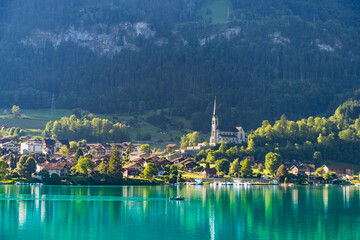 Fototapeta na wymiar Swiss village Lungern with traditional houses, old church Alter Kirchturm along lovely emerald green lake Lungerersee, canton of Obwalden Switzerland