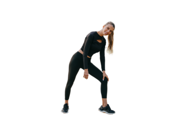 Cheerful blonde caucasian girl in black sportswear standing against transparent background. Fit American young adult woman warming up before jogging. Healthy women.