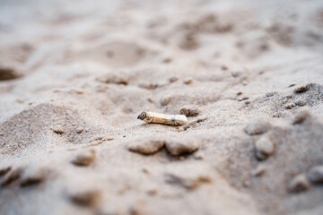 Fototapeta na wymiar A used cigarette on the beach on the sand