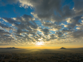 Ethereal Sunset Symphony with Scattered Clouds and Gentle Fog Blanket over the Mojave Desert