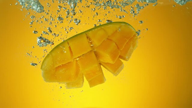 Super slow motion of falling fresh mango into water on orange gradient background. Filmed on high speed cinema camera, 1000 fps.