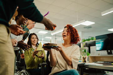 Jolly birthday girl is having a birthday cake at the office form diverse team.