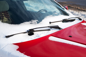 Close up of frozen windshield and red car wiper in winter. 
Snow-covered car windshield. Wipers and washers in frost. Frost and cars.