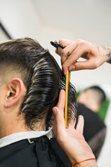 Fototapeta premium barber's hand with comb and scissors cutting the hair