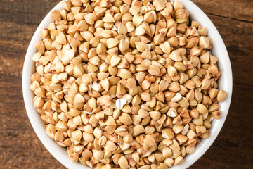 Buckwheat grains in bowl on rustic wooden table. Top view