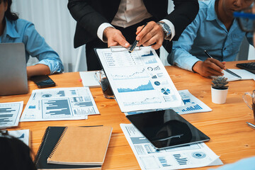 Diverse group of business analyst team analyzing financial data report paper on office table. Chart and graph dashboard by business intelligence analysis for strategic marketing planning Habiliment