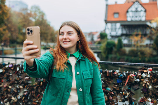Redhead girl making selfie photo on city street in Gdansk. Traveling Europe in autumn. Vacation concept