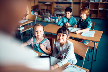 Elementary school kids listening to teacher in classroom
