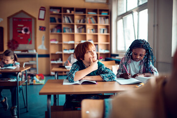Diverse children writing notes in elementary classroom