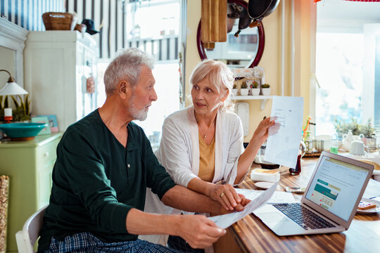 Senior woman showing phone bill to husband at home