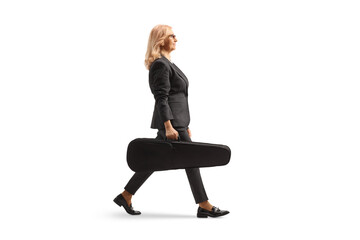 Full length profile shot of a woman walking and carrying a violin in a case
